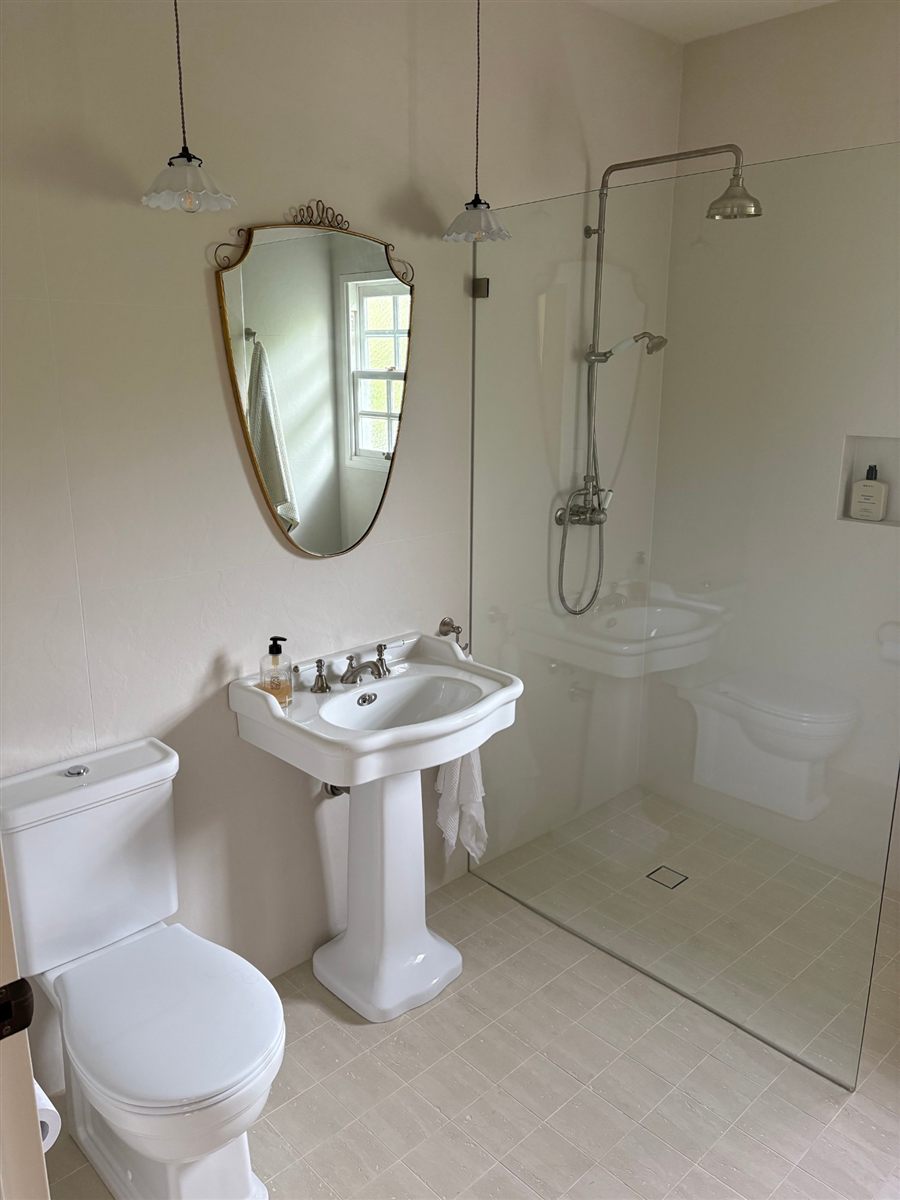 Renovated bathroom with pedestal basin and rail shower